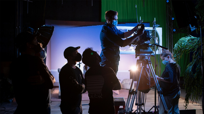 People on a production set are working around a camera.