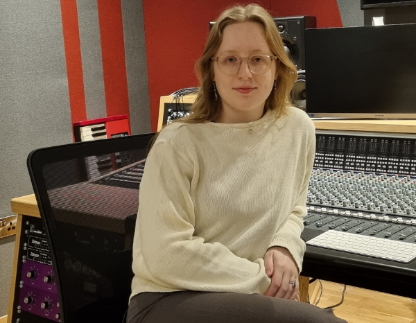 Female programme participant in front of an SSL mixing console. 