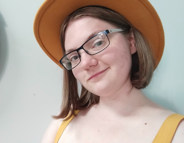 A young woman in yellow, smiling at the camera